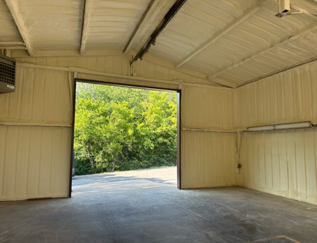 Open warehouse with spray foam insulation on the walls and ceiling.